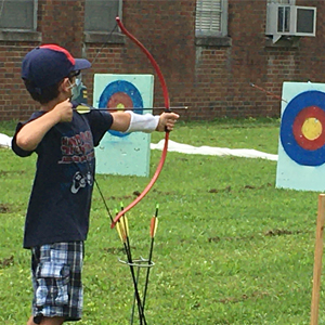 Cub Scout aiming a bow and arrow