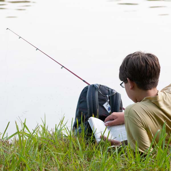 Scout reading a book while fishing