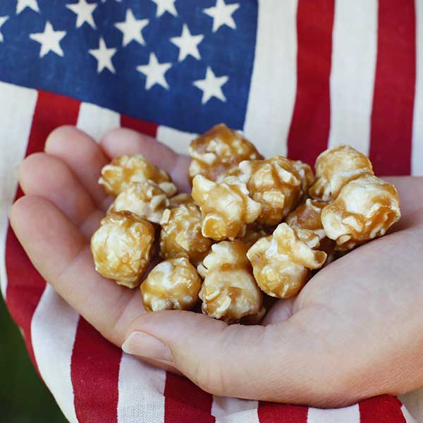 Hand holding popcorn in front of an American flag