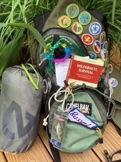 Camping gear and Scout sash with merit badges