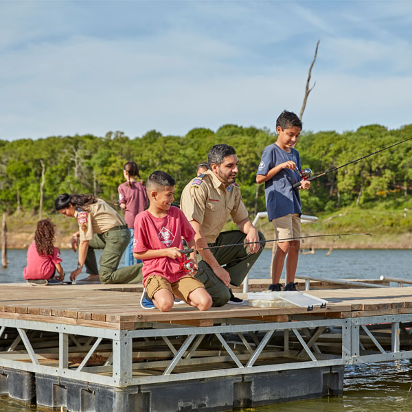 Photo of two Scout leaders and four Scouts fishing on a pier