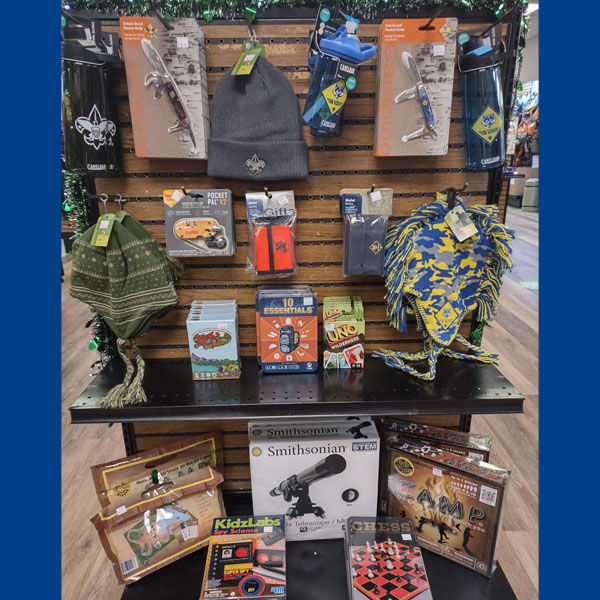Photo of holiday gifts available at the Scout Shop, including hats, card games, pocket knives, water bottles, and science kits