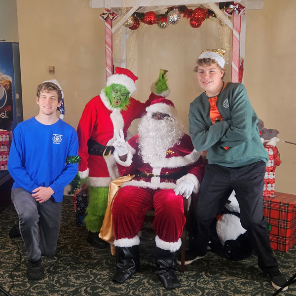 Scouts posing with Santa Claus and the Grinch
