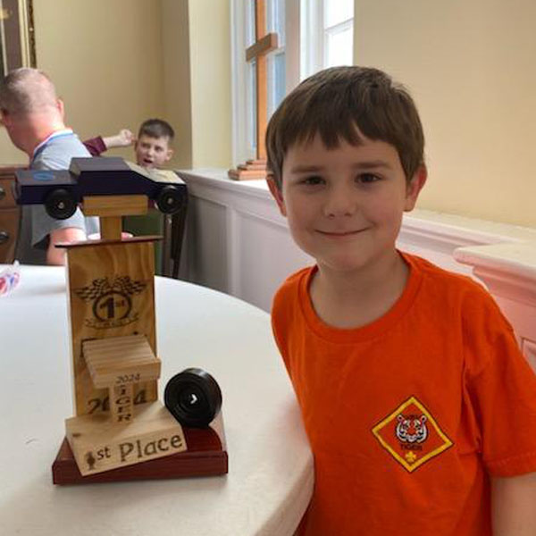 Tiger Cub Scout with Pinewood Derby car and trophy