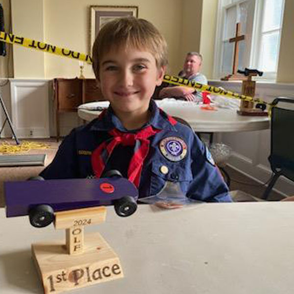 Wolf Cub Scout with Pinewood Derby car