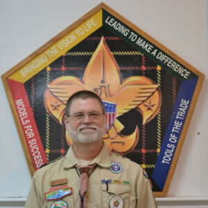 Photo of Mike Zemienieuski in front of a Wood Badge logo